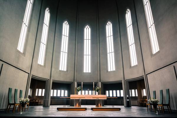 Innenraum einer modernen Kirche mit hohen, gotischen Fenstern und schlichtem Altar, dekoriert mit Blumen.