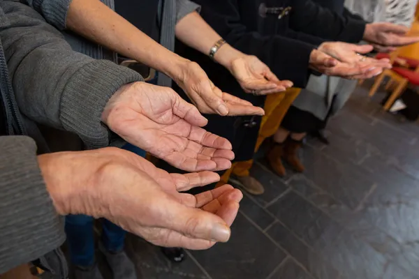Gruppe betet inGemeinschaft mit nach oben geöffneten Händen.
